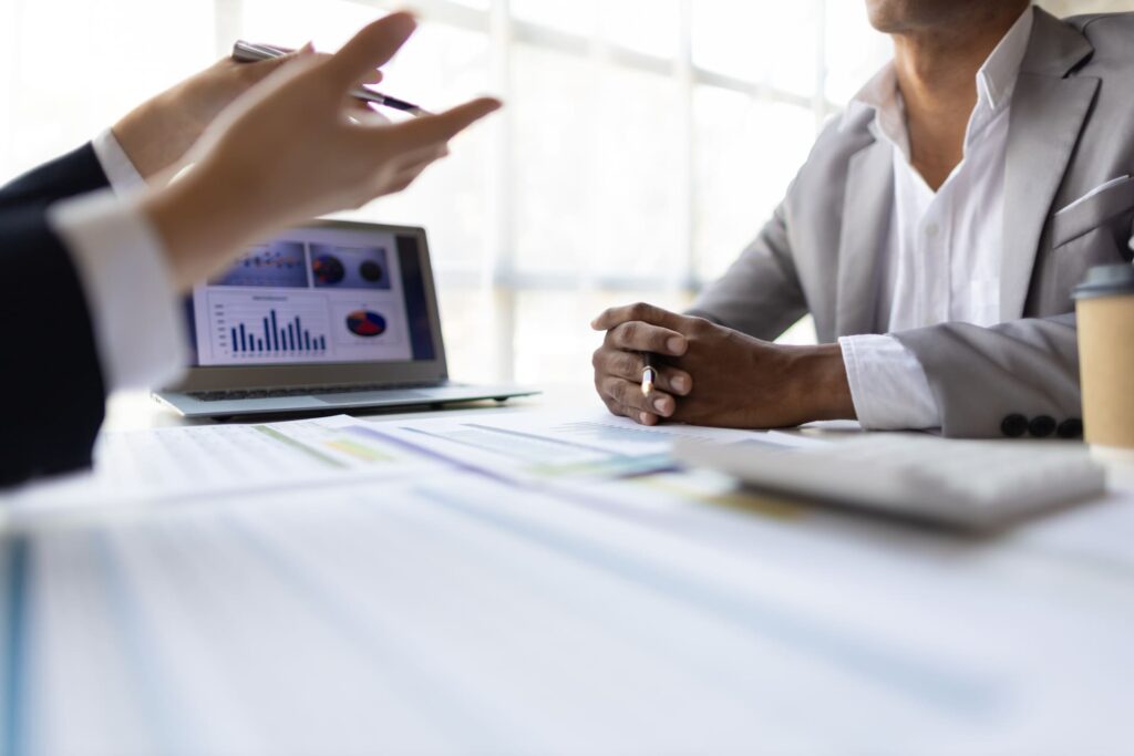 Business discussion with charts displayed on a laptop screen