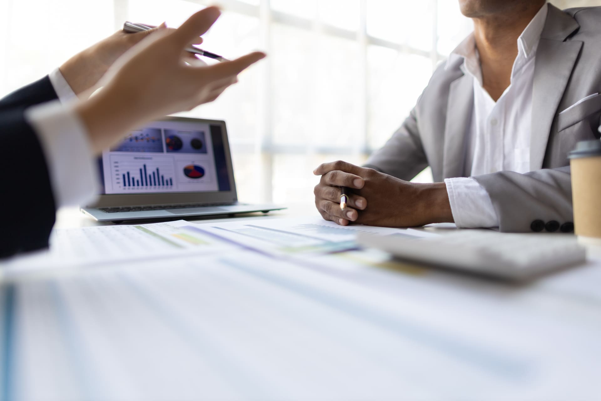 Business discussion with charts displayed on a laptop screen