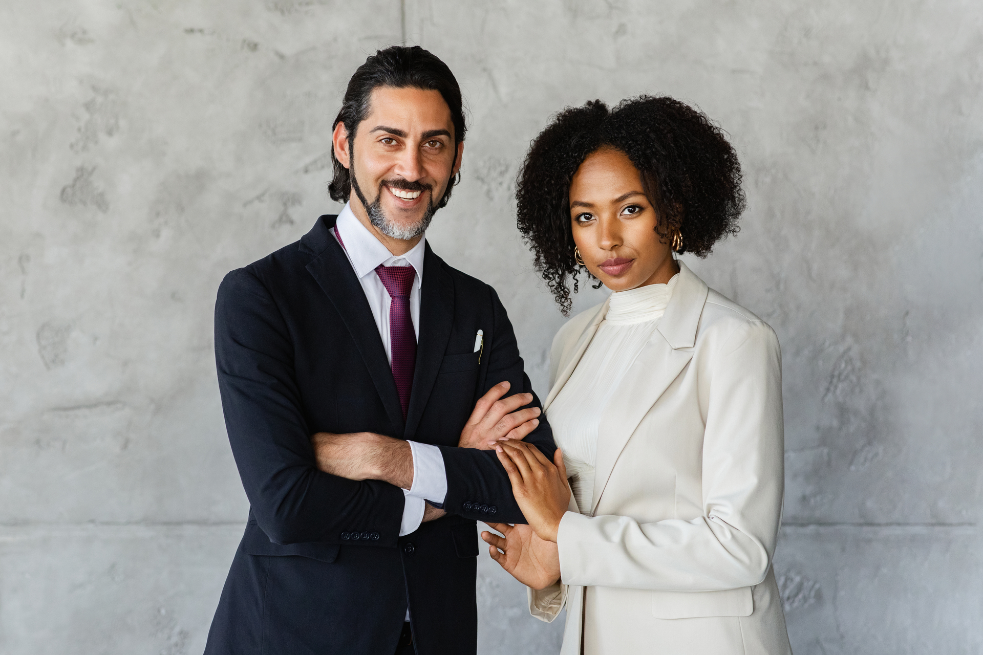 Businessman-and-businesswoman-turning-around-and-smiling-while-walking-outside-a-modern-office-building-both-dressed-in-light-colored-suits