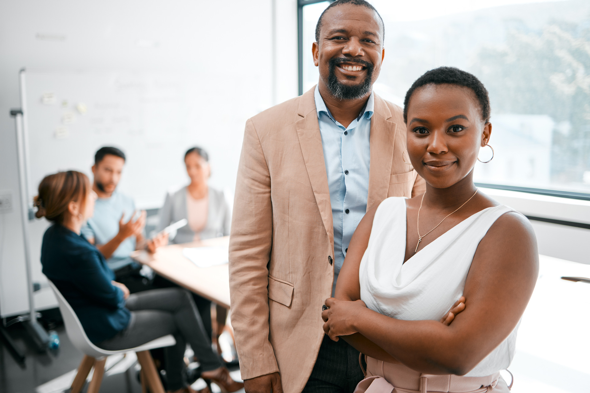 Confident-business-partner-standing-in-the-forground-of-a-meeting-room