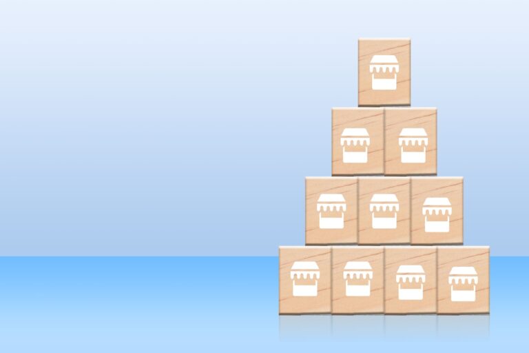 Pyramid of wooden blocks with store icons showing franchise expansion