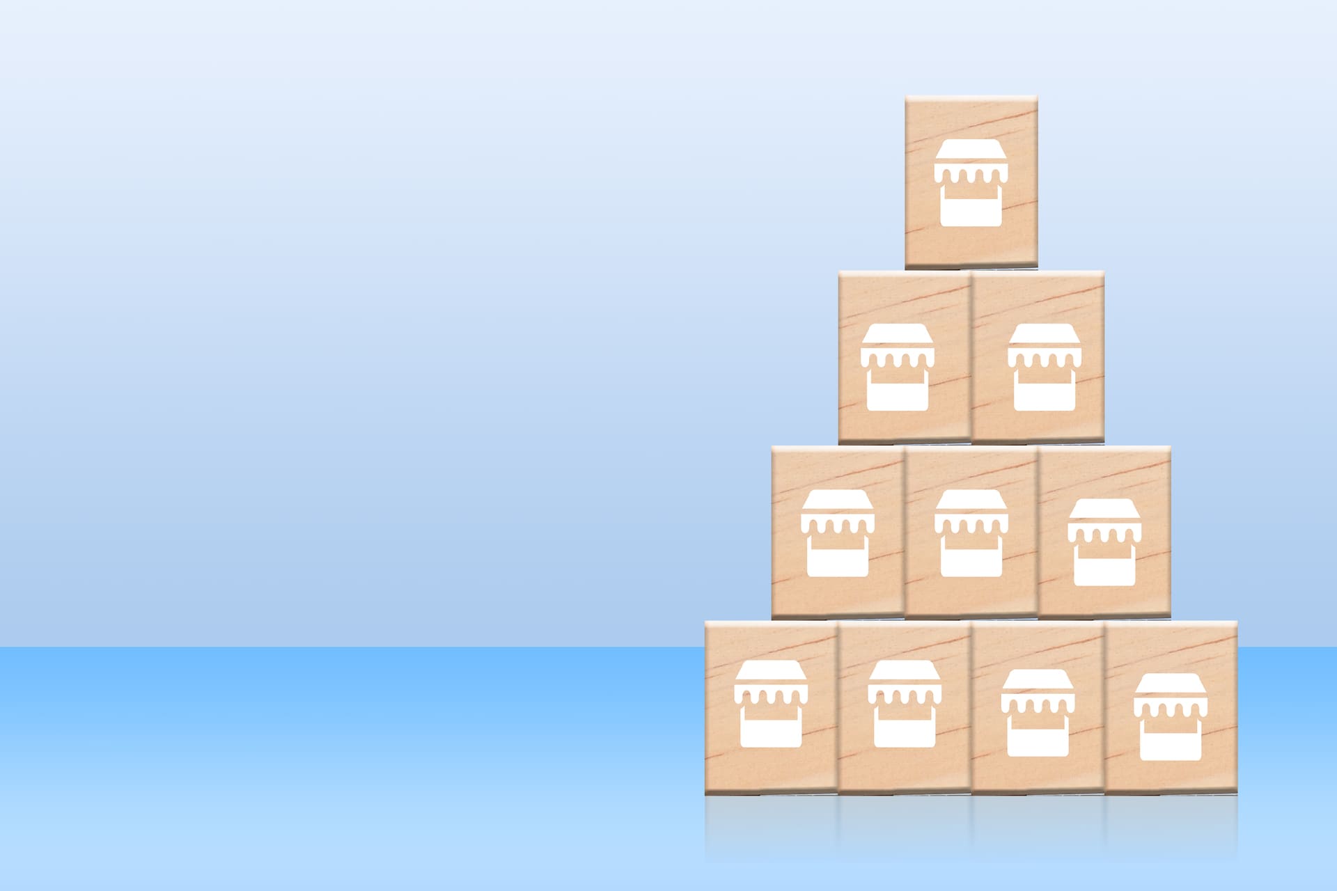 Pyramid of wooden blocks with store icons showing franchise expansion