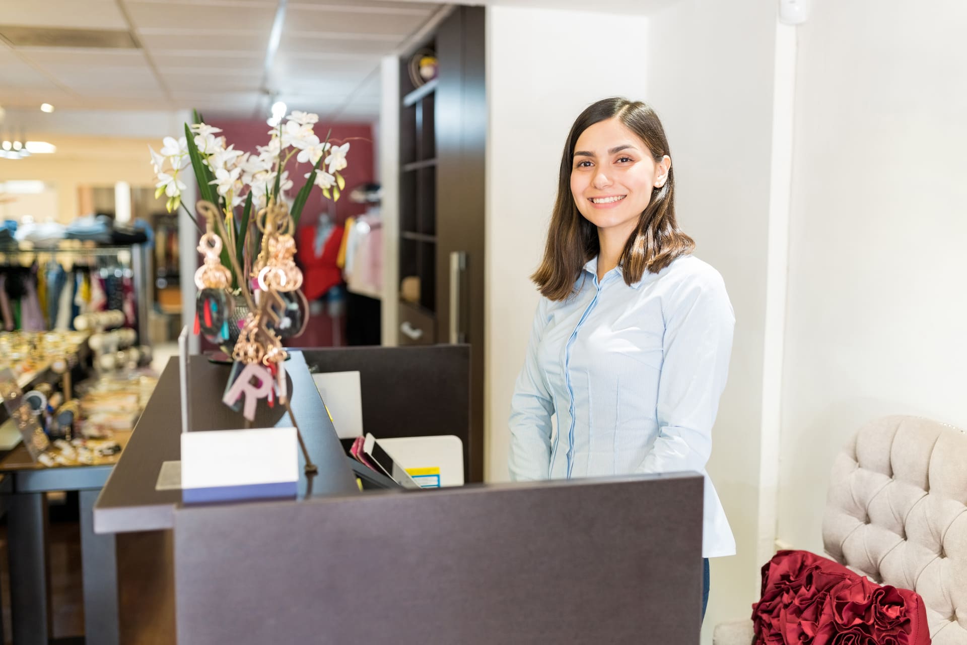 Smiling shop assistant behind counter in clothing store