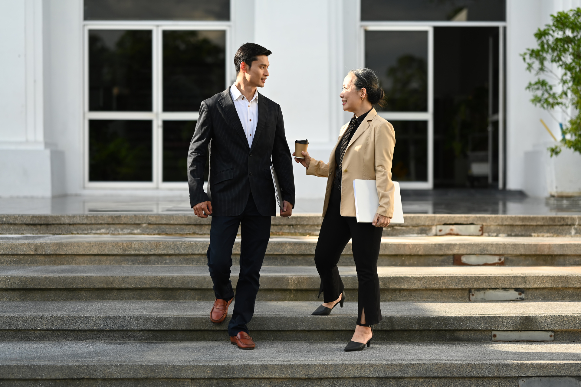 Two-business-professionals-walking-down-the-building-steps-engaged-in-a-conversation
