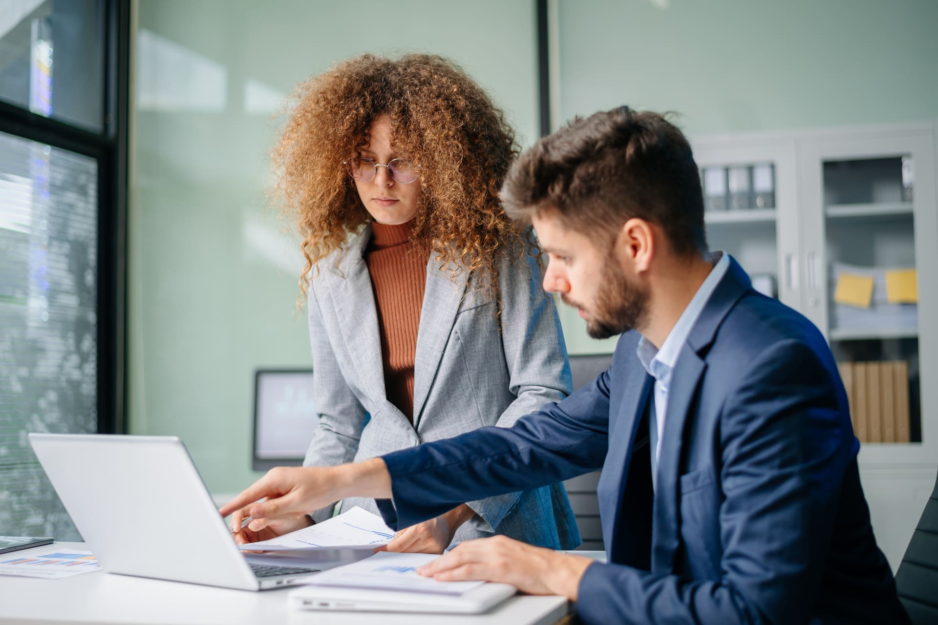 Two colleagues analyzing financial data on a laptop