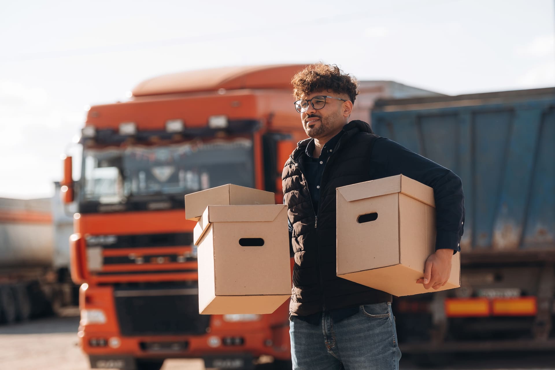 Warehouse worker carrying boxes in front of truck