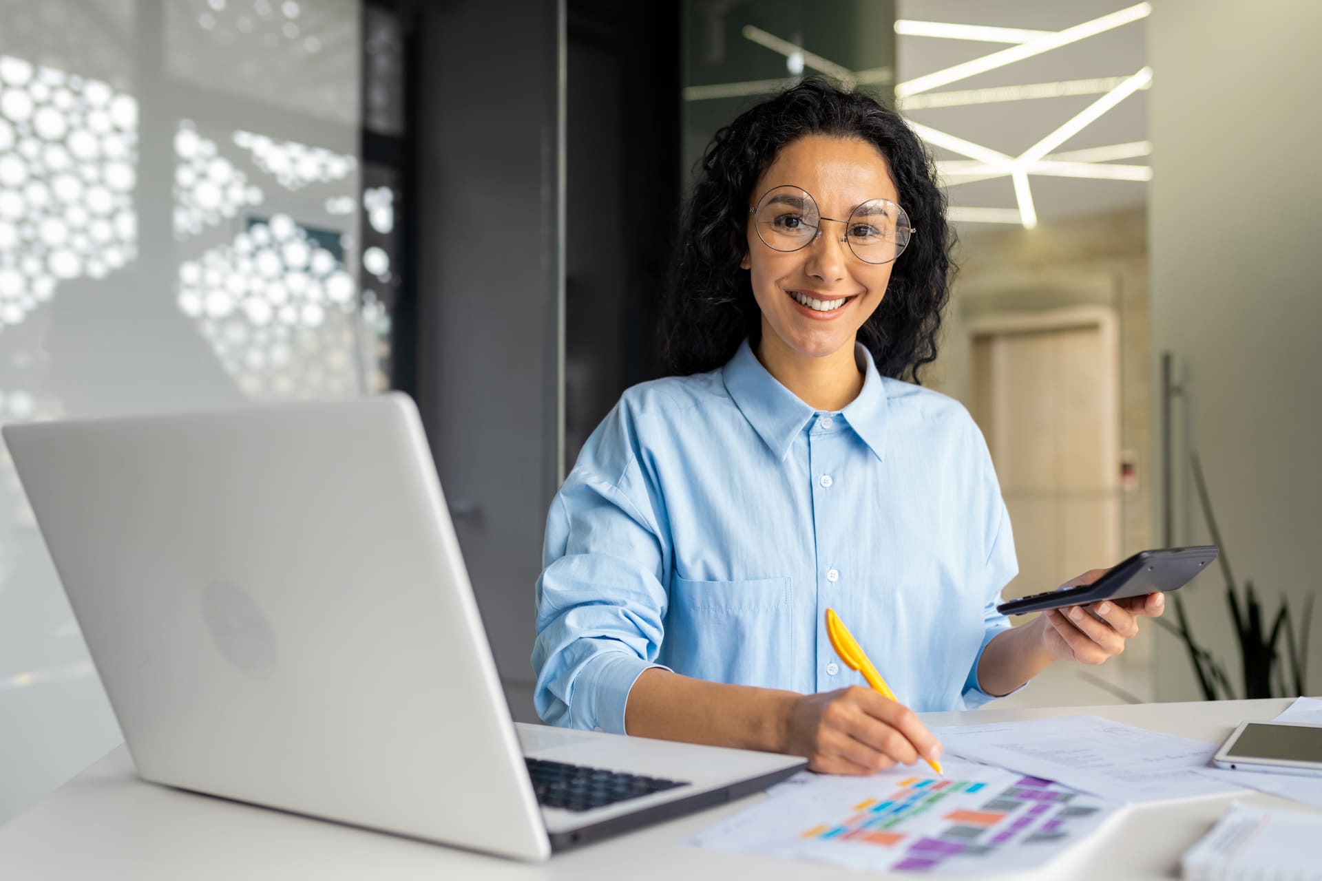 Smiling businesswoman working with laptop and calculator