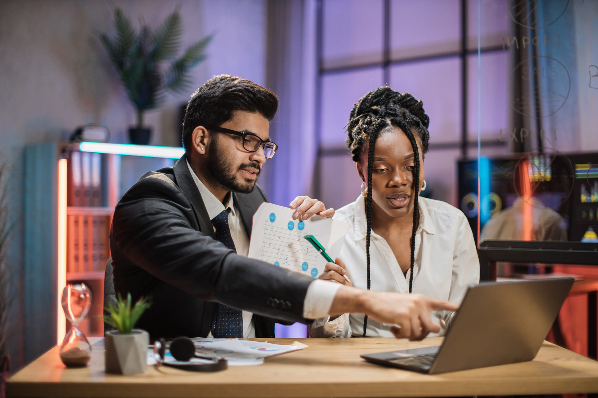 Two professionals analyzing financial report on laptop