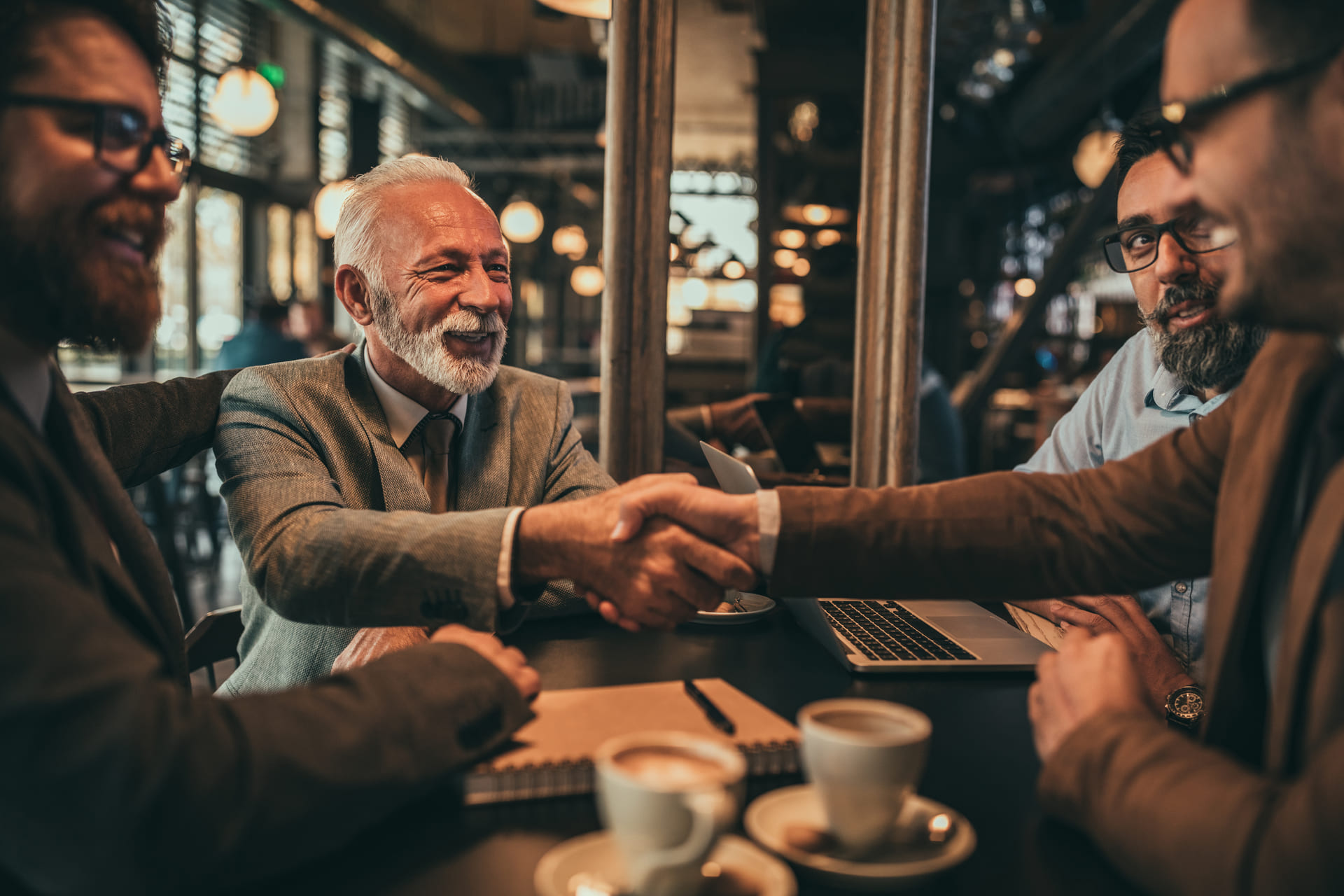 businessmen-shaking-hands-during-meeting-at-cafe
