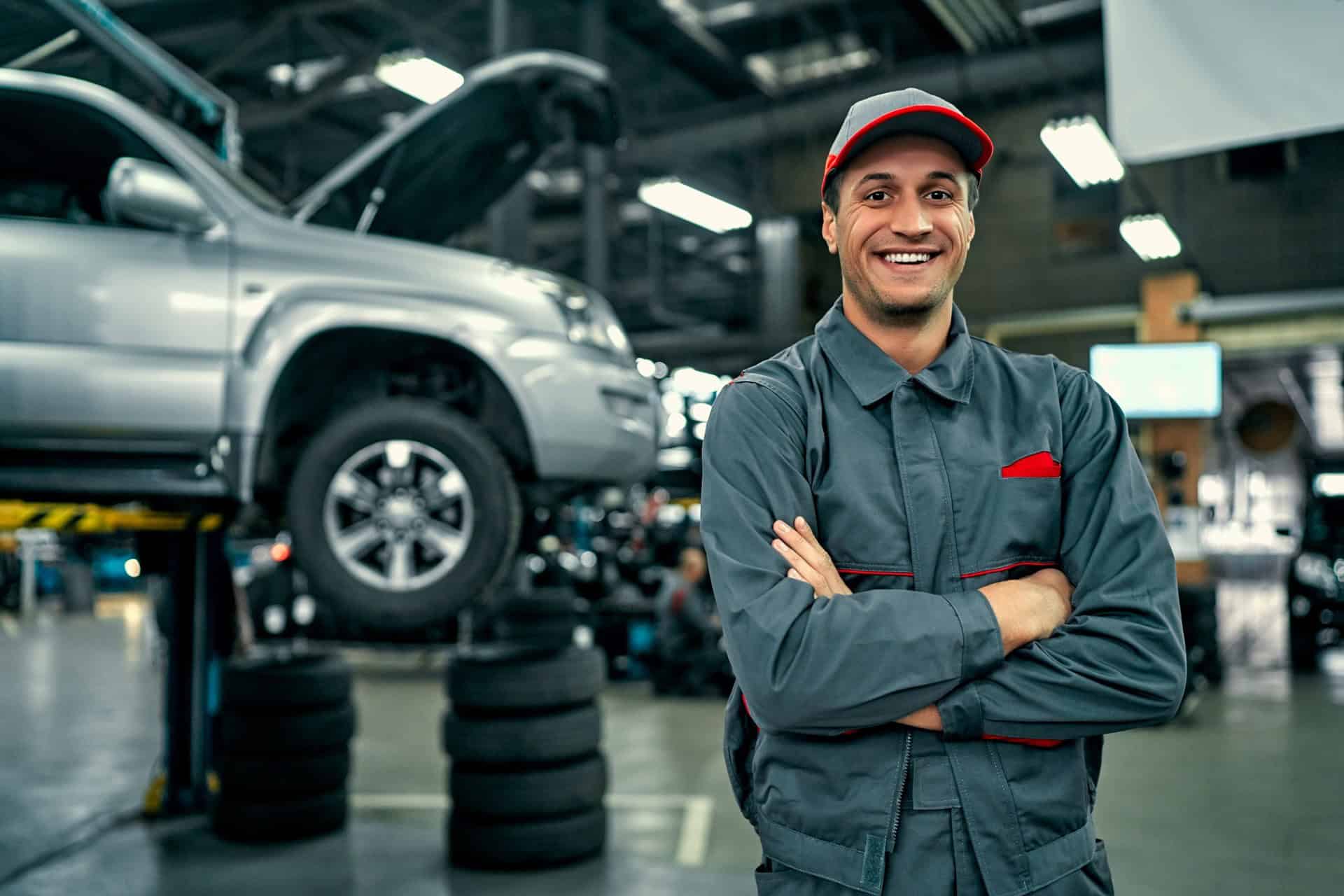 Auto-mechanic-standing-beside-vehicle-in-repair-shop
