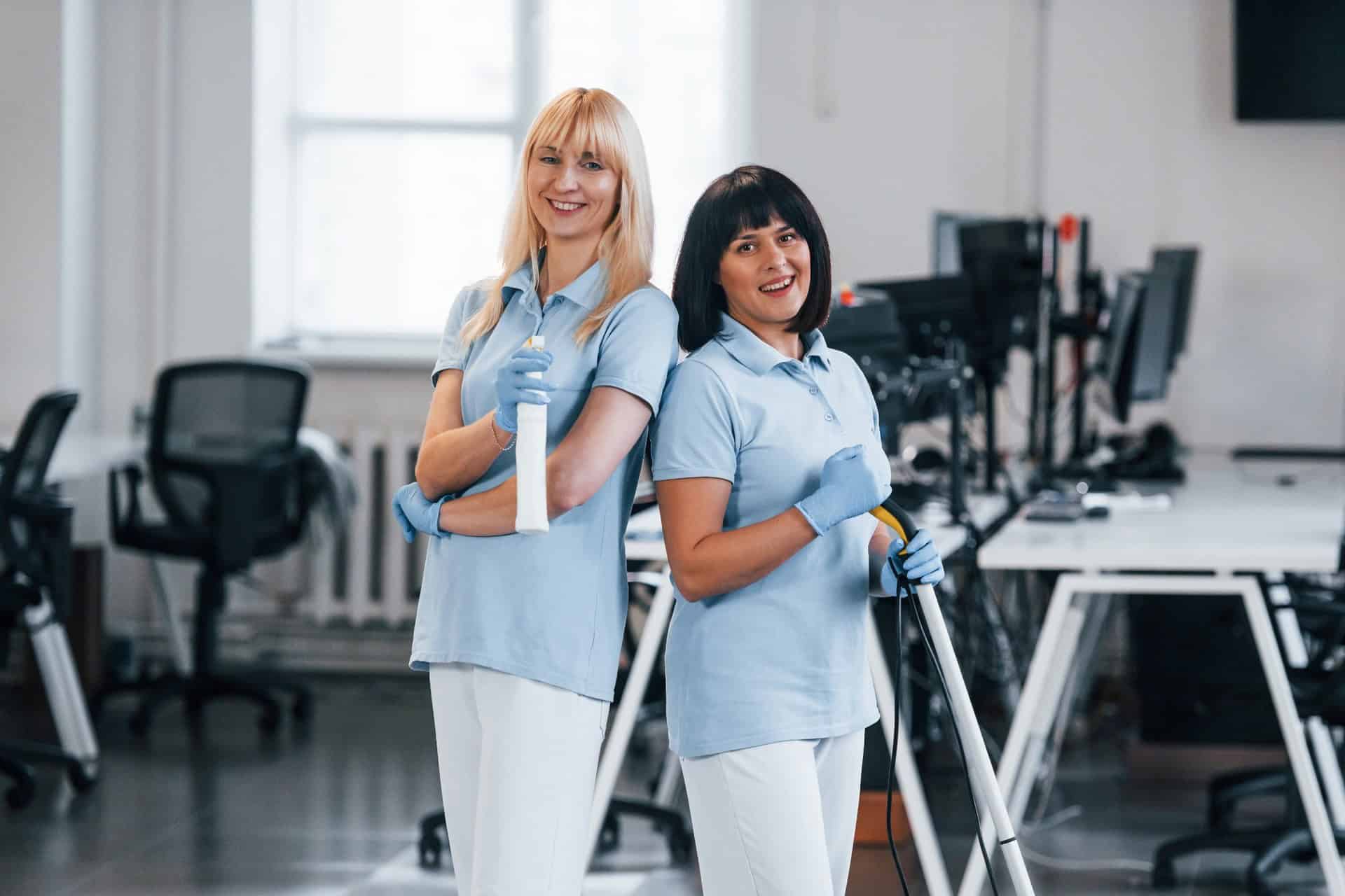 Professional-cleaners-standing-with-supplies-in-modern-office