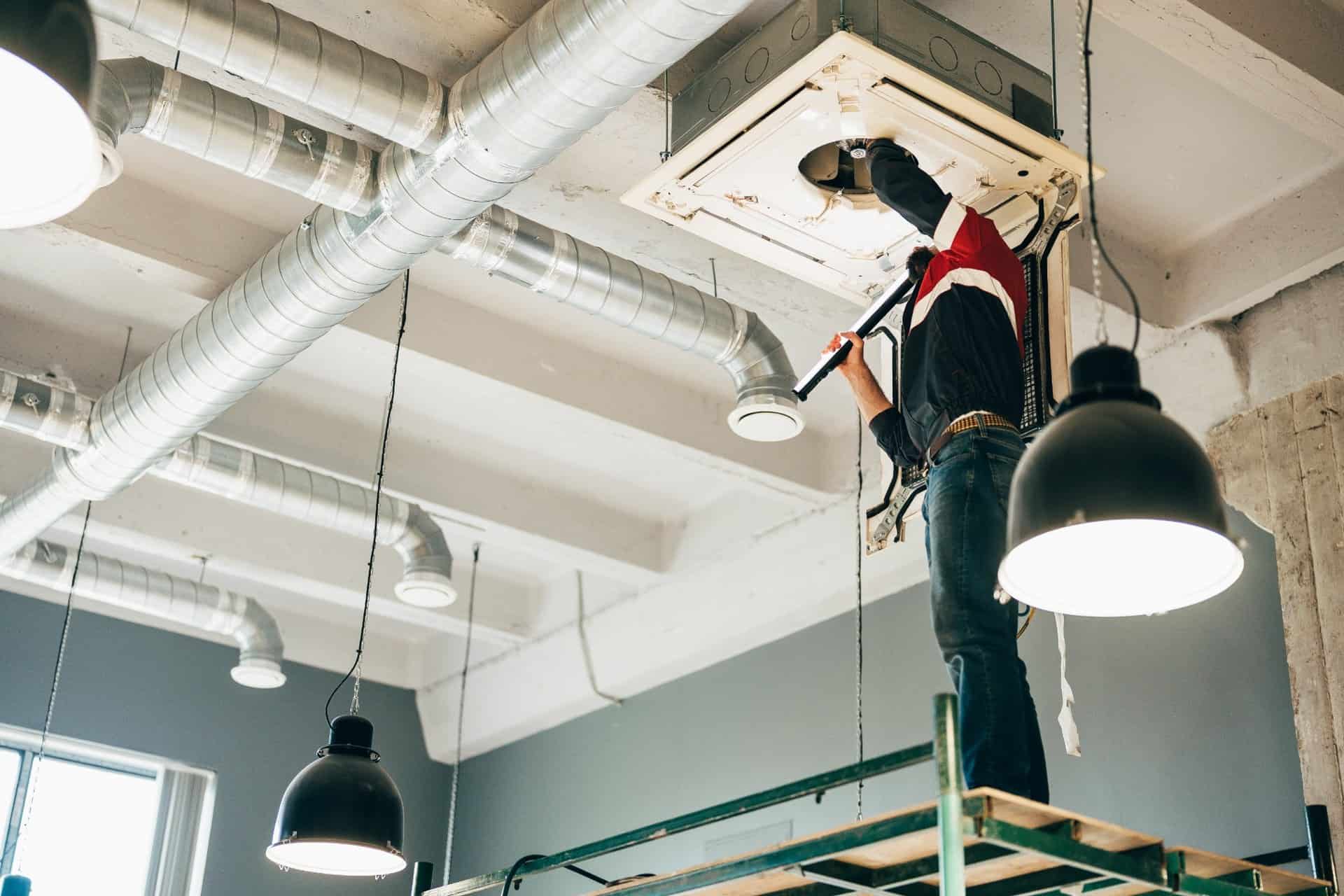 Technician-repairing-ceiling-HVAC-unit-in-commercial-building