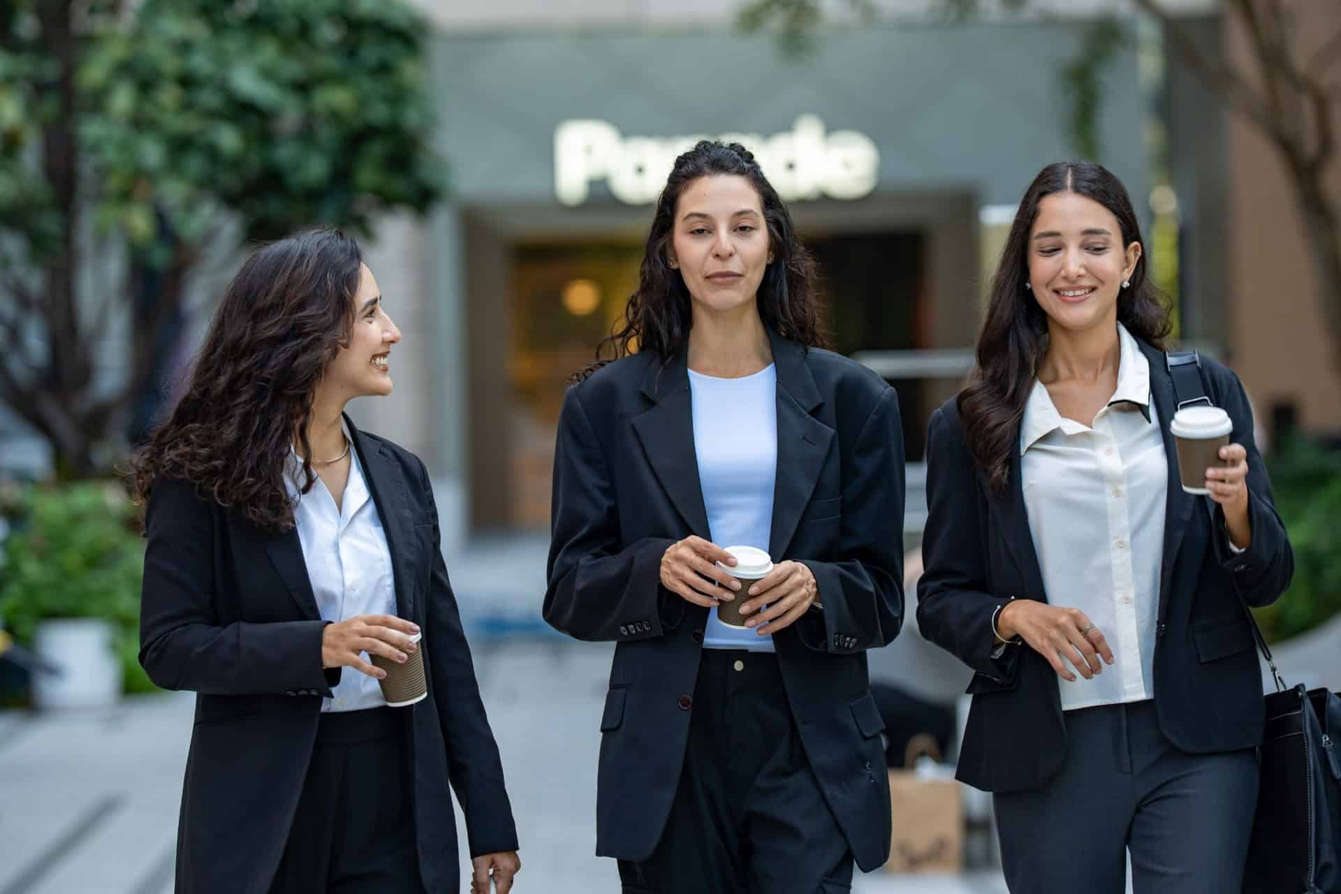 Three-professional-women-walking-and-talking-with-coffee