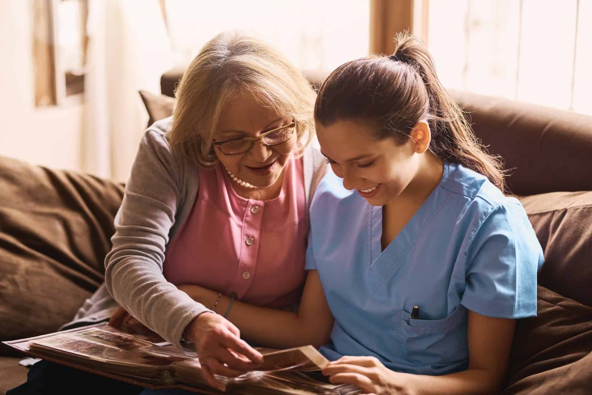 Senior woman looking through photo album with caregiver