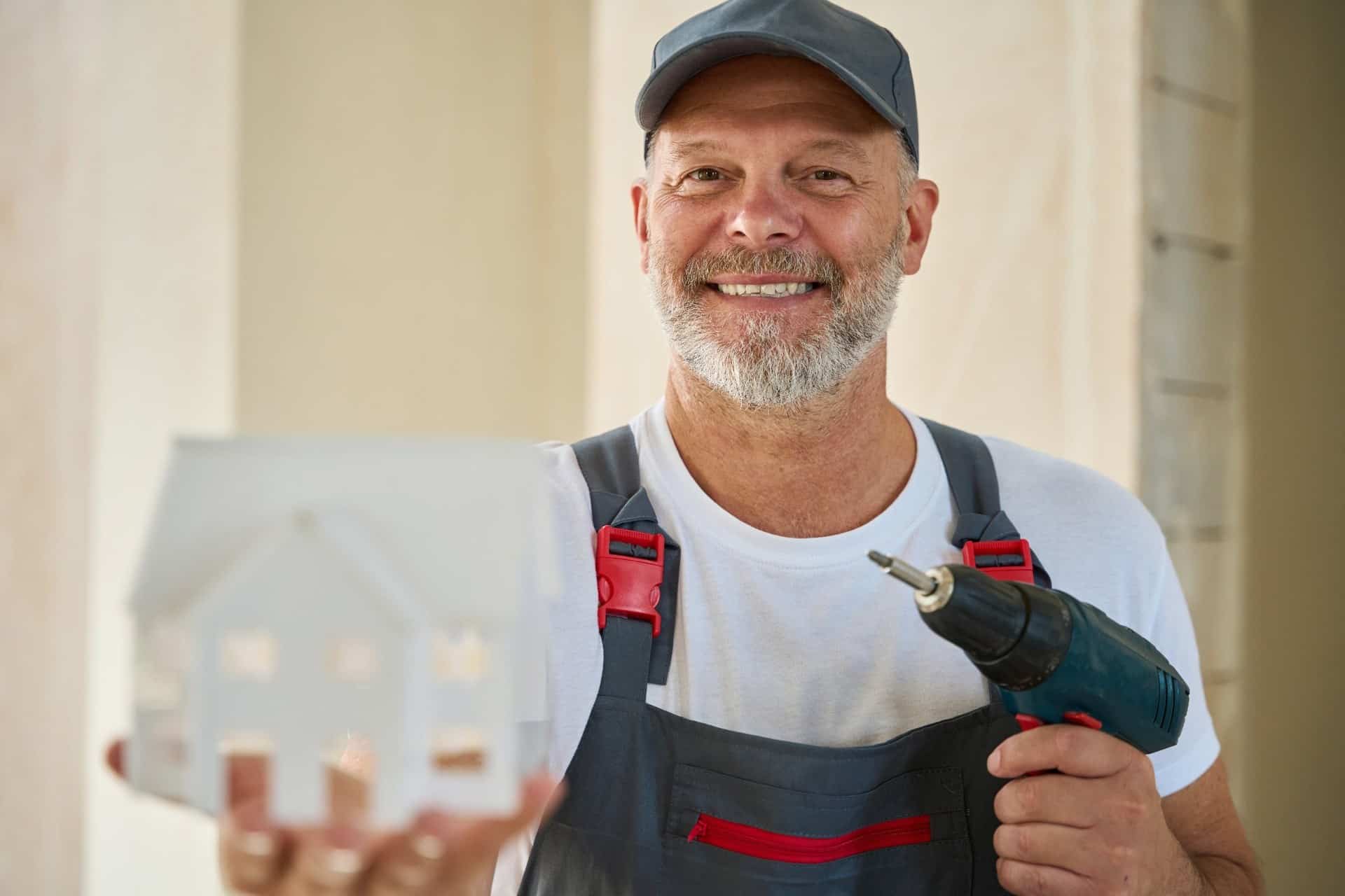 Construction worker holding a house model and power drill