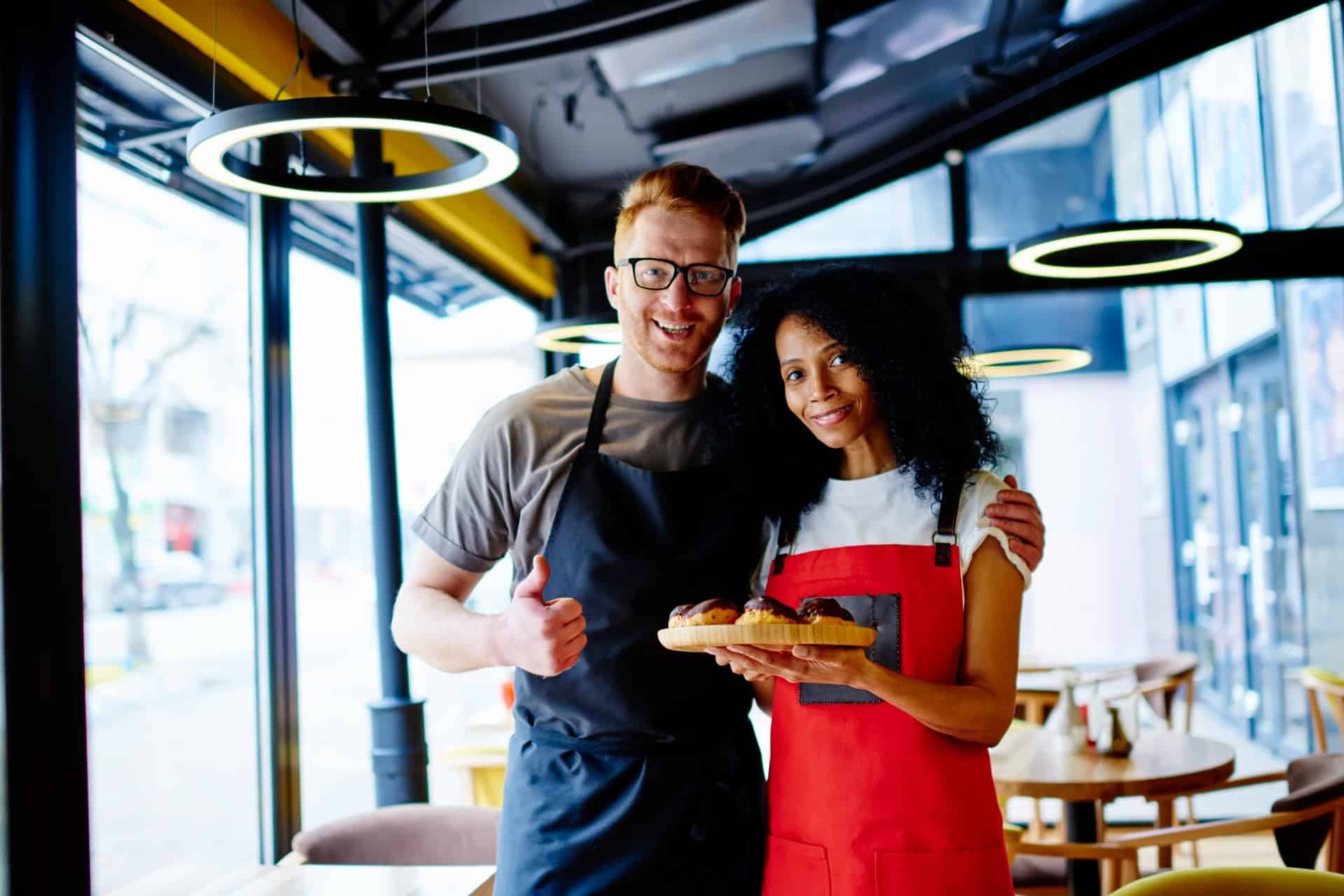 Restaurant employees holding freshly prepared pastries for customers