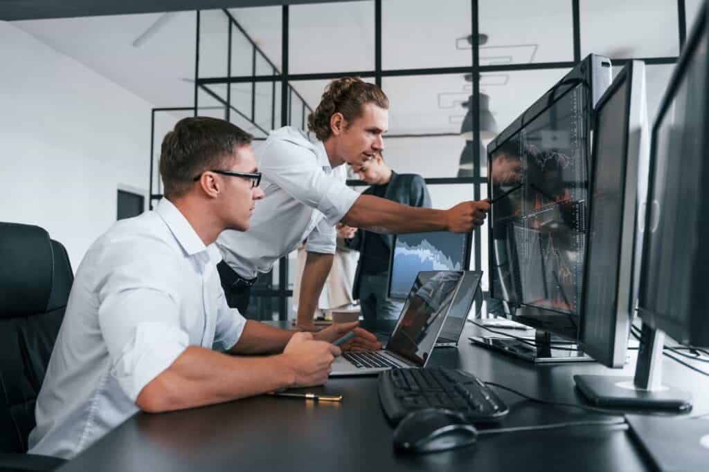 Business team analyzing data on multiple computer screens